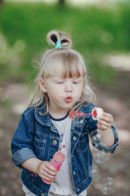 Free photo little blond girl blowing by a pompous and making bubbles