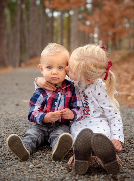 Free Photo little blonde siblings hugging and sitting on the ground in a forest in texas