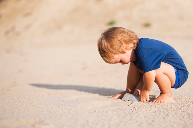 Little boy at beach playing with sand