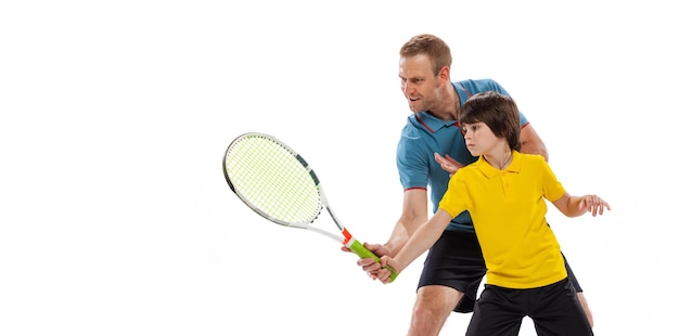 Free photo little boy child learning how to play tennis with professional sport instructor isolated over white studio background