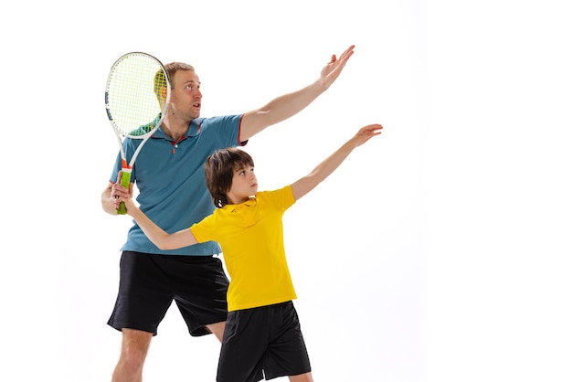 Free photo little boy child learning how to play tennis with professional sport instructor isolated over white studio background