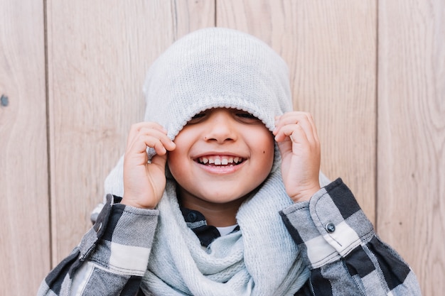 Free Photo little boy covering eyes with winter cap 