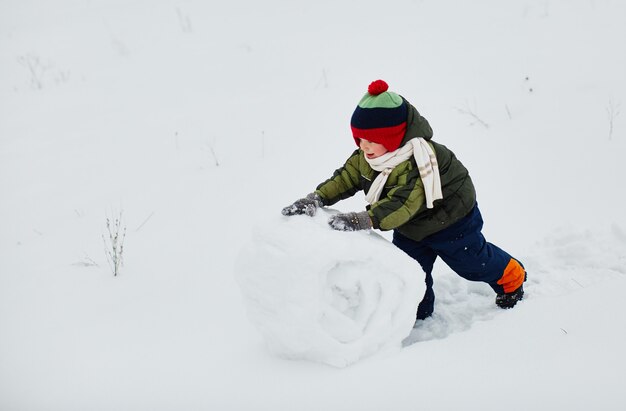 A little boy creates a snowman