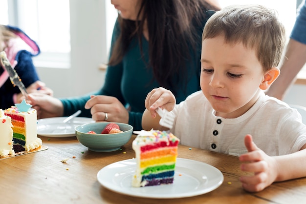 Little boy eating a rainbow colored cake