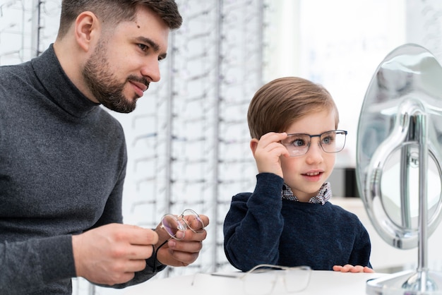 Little boy and father in store trying on glasses