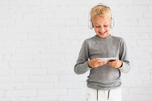 Little boy having fun with smartphone and earphones