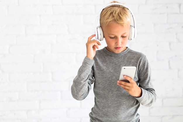 Little boy having fun with smartphone and earphones