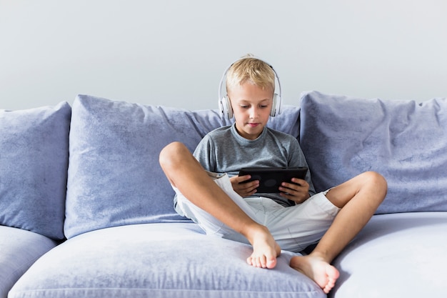 Little boy having fun with tablet and earphones