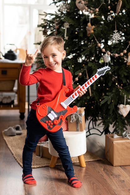 Free photo little boy holding a guitar