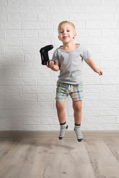 Free photo little boy holding joystick and jumping