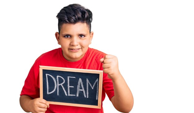 Little boy kid holding blackboard with dream word annoyed and frustrated shouting with anger yelling crazy with anger and hand raised