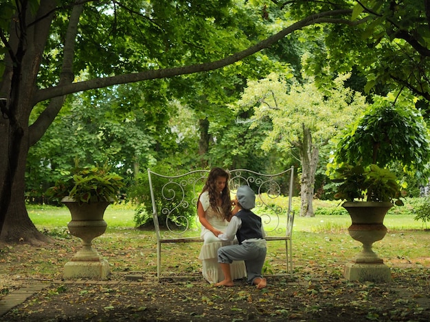 Free photo little boy kneeled before a little girl in a garden