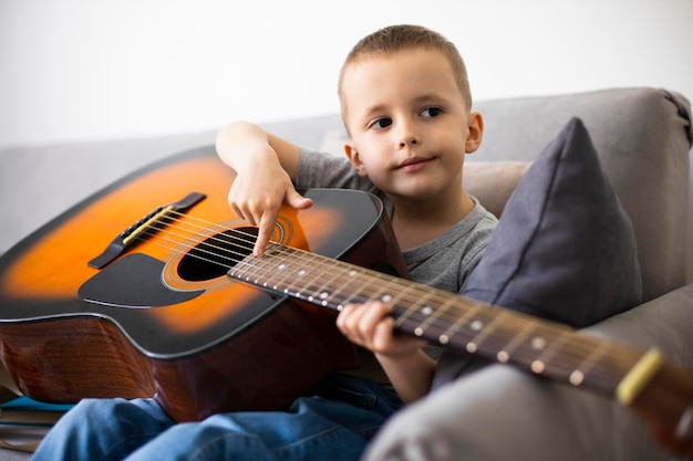 Free photo little boy learning how to play guitar