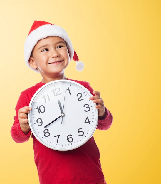 Little boy looking up while holding a clock