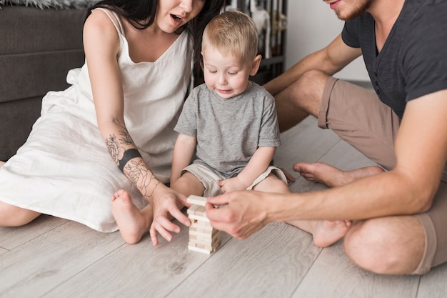 Little boy looking at wooden blocks stacking by his parents at home