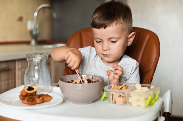 Little boy mixing cereals in a bowl