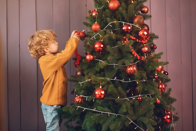 Little boy near christmas tree in a brown sweater