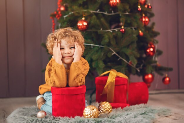 Free photo little boy near christmas tree in a brown sweater