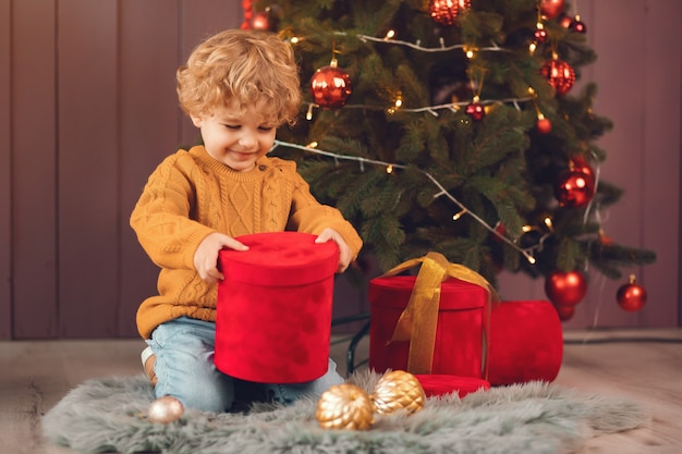 Little boy near christmas tree in a brown sweater