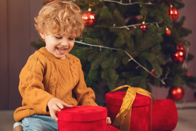 Little boy near christmas tree in a brown sweater