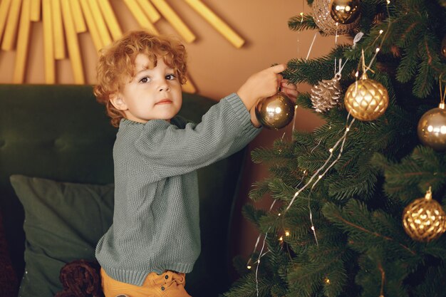 Free photo little boy near christmas tree in a gray sweater