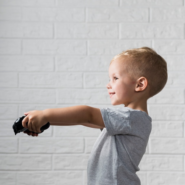 Free photo little boy playing digital games with joystick