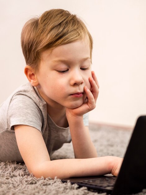 Little boy playing on the floor with his laptop