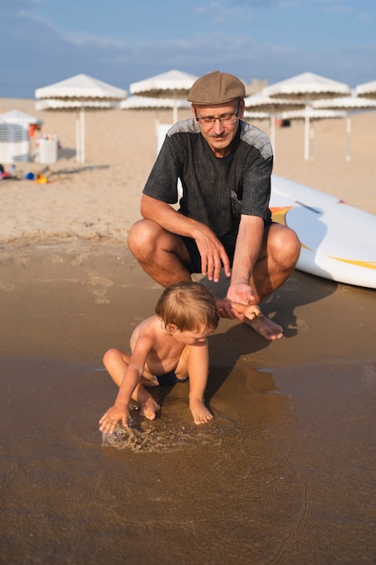 Little boy playing in water with grandpa beside