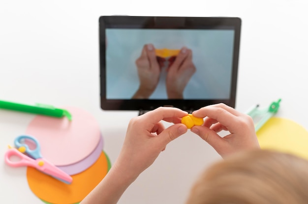 Free photo little boy playing while looking at tablet