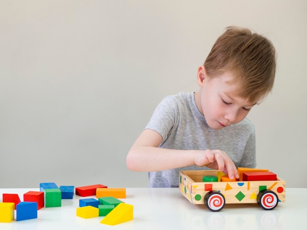 Free photo little boy playing with wooden car