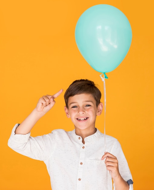 Little boy pointing to his blue balloon 