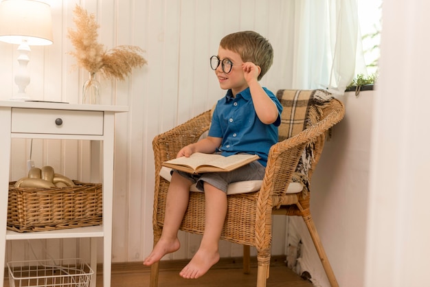 Little boy reading while sitting in an armchair