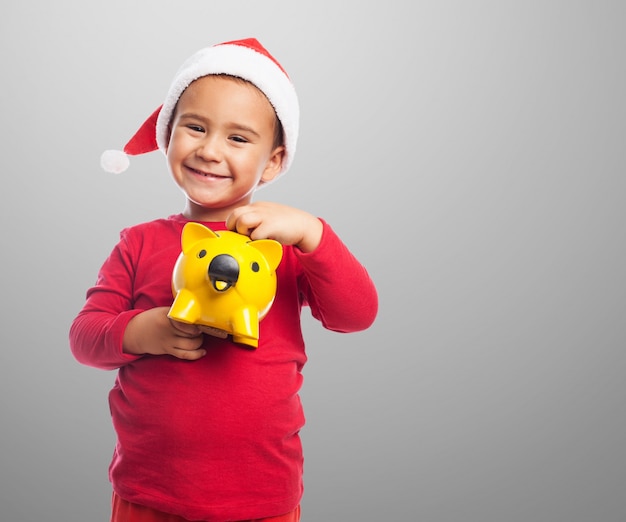 Little boy showing his yellow piggybank