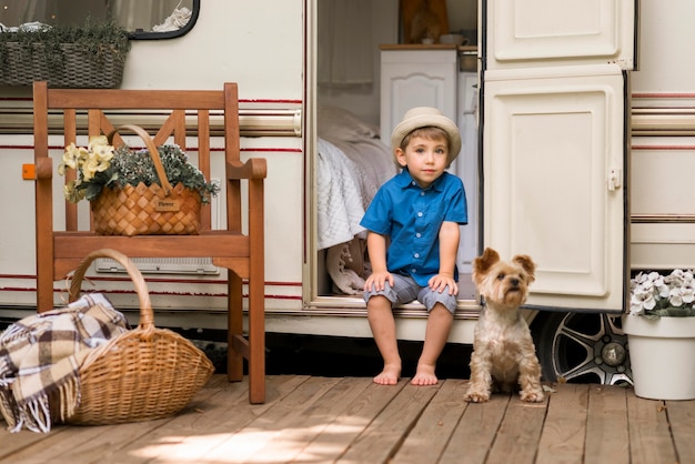 Free Photo little boy sitting on a caravan next to a cute dog