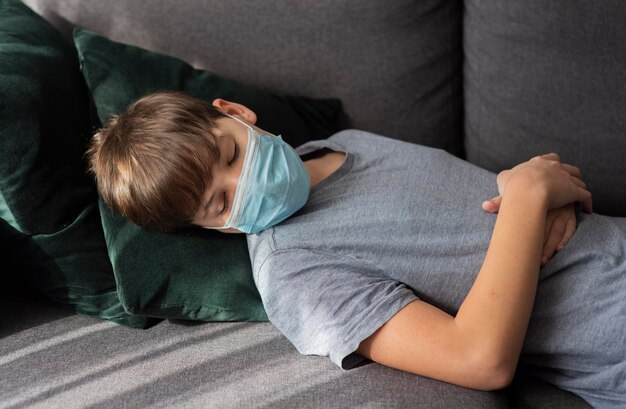 Little boy sleeping with a medical mask on