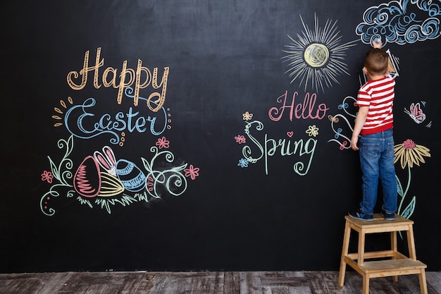 Little boy standing and drawing easter doodles