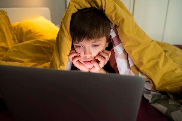 Free photo little boy watching films on the laptop