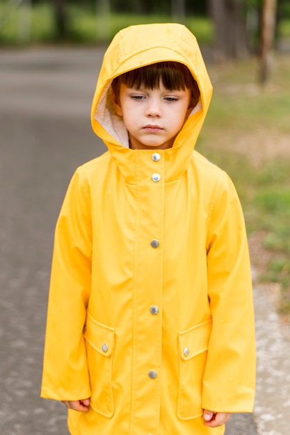 Free Photo little boy wearing yellow rain coat