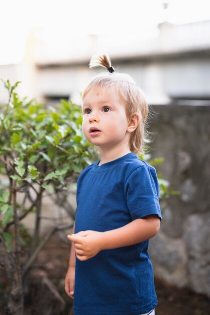 Little boy with hair tail looking away 