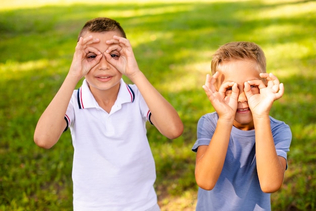 Little boys making fake glasses with their fingers