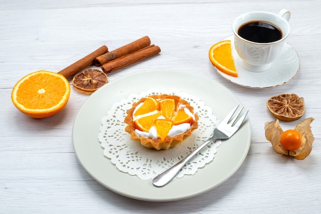 little cake with cream and sliced oranges along with coffee and cinnamon on light desk, fruit cake biscuit sweet sugar