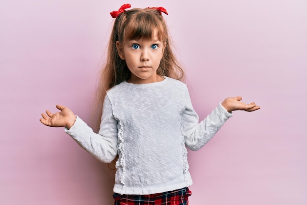 Little caucasian girl kid wearing casual clothes clueless and confused with open arms, no idea and doubtful face.