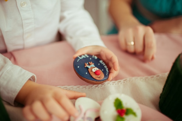 Free photo little child holds cookie with lettering 'let it snow'