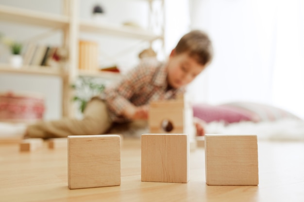 Free photo little child sitting on the floor pretty boy palying with wooden cubes at home