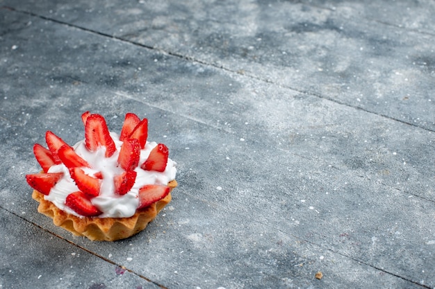 Free photo little creamy cake with sliced strawberries on grey wooden desk, fruit berry cake sweet color