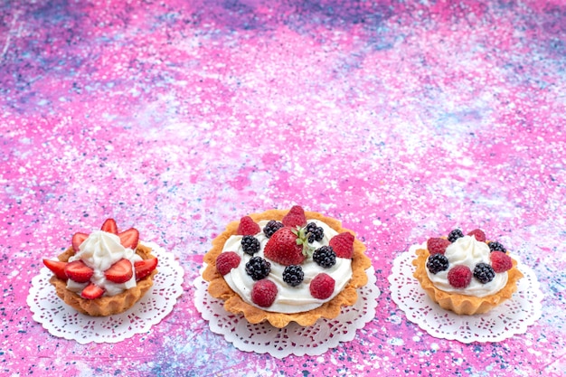 Free photo little creamy cakes with different berries on light white, cake berry sweet bake