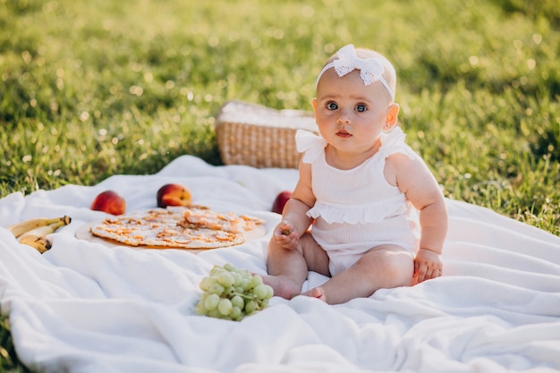 Little cute baby girl sitting on blanket in park