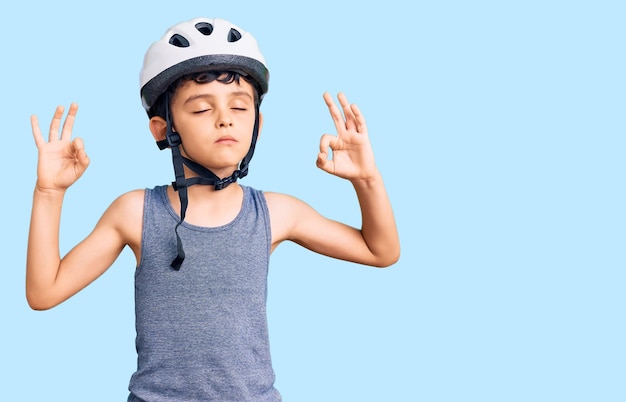 Little cute boy kid wearing bike helmet relax and smiling with eyes closed doing meditation gesture with fingers. yoga concept.