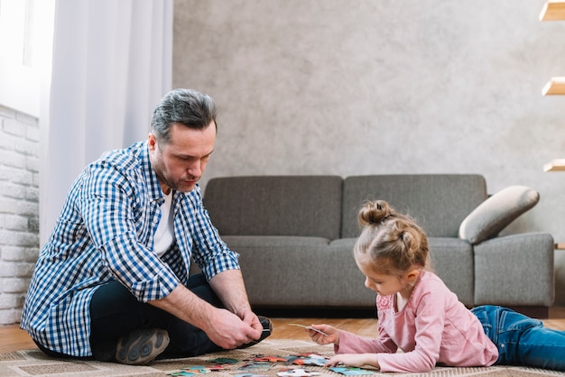 Little daughter and father playing jigsaw puzzle at home