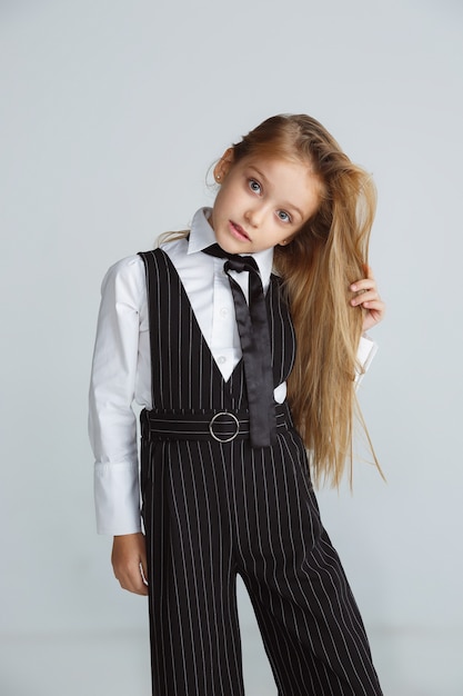 Free photo little female caucasian model posing in school's uniform on white  background.